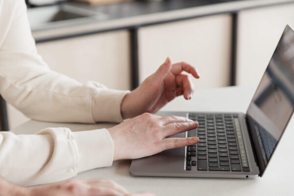 Studio Cotton's Aime's hands using an Apple Macbook laptop.